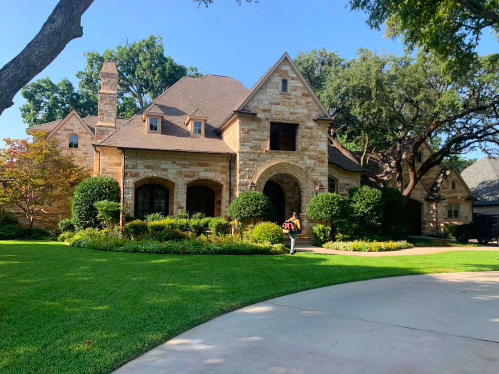 Dallas lawn care services: freshly mowed front lawn and trimmed beds at a stone home